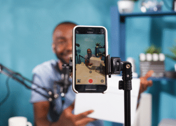 Homem gravando vídeo com smartphone em tripé para criação de conteúdo digital.