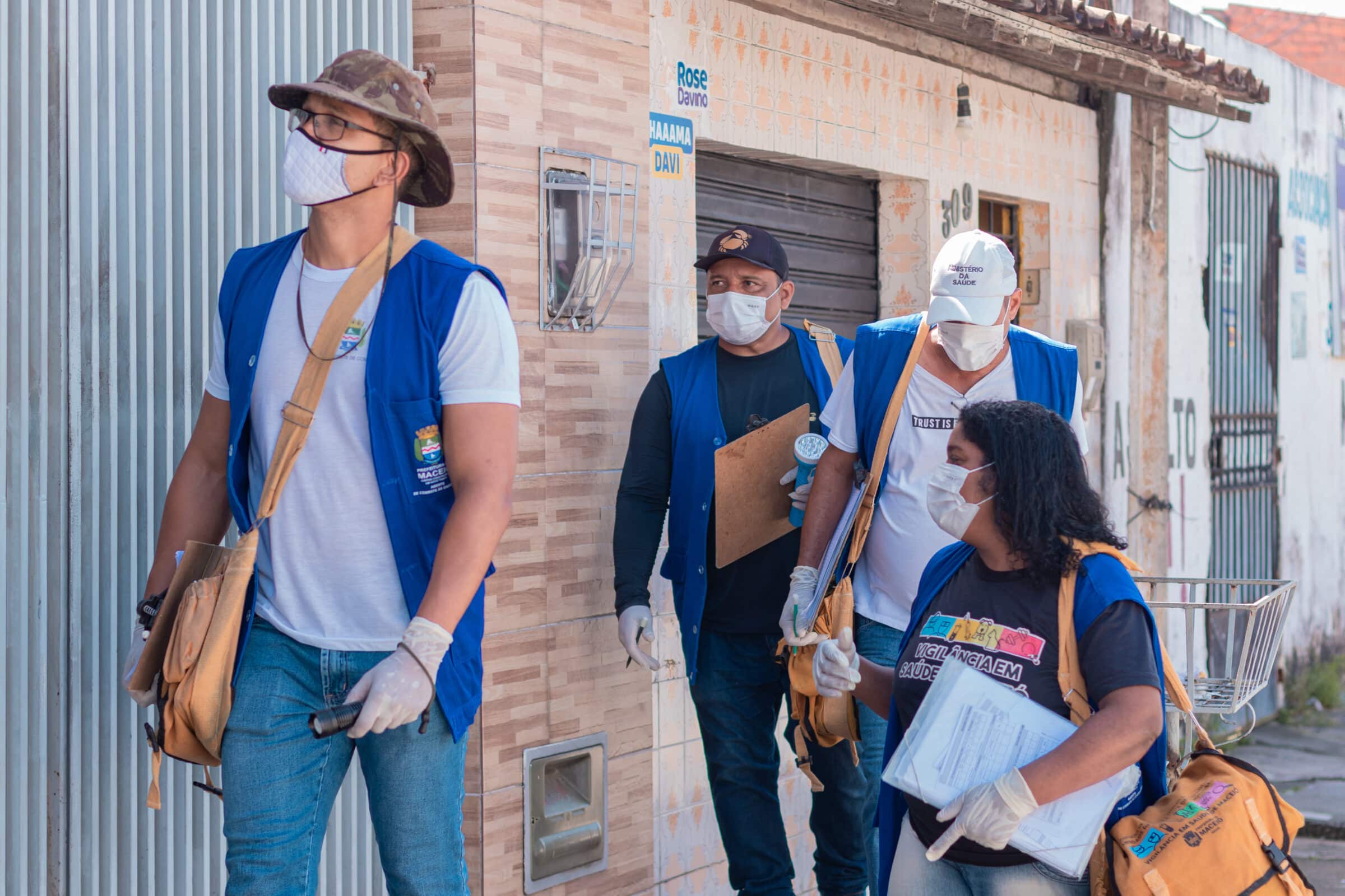 Agentes Comunitários de Saúde e Endemias, uniformizados, realizando trabalho de campo e prevenção em bairro residencial.