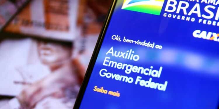 Imagem de celular exibindo a tela do Auxílio Emergencial do Governo Federal, com fundo de cédulas de dinheiro.