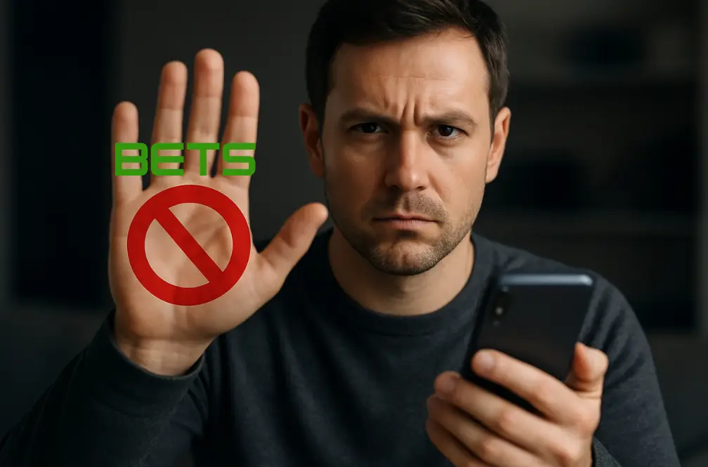 Homem com expressão séria, segurando um celular e fazendo gesto de 'não' com a mão, com o texto 'BETs' e símbolo de proibição sobre a mão."