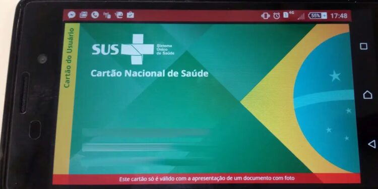 Cartão Nacional de Saúde do SUS exibido em tela de smartphone com bandeira do Brasil ao fundo