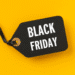 Etiqueta preta com fita e a frase “Black Friday” em fundo amarelo.