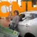 Mulher sorridente segura chave do carro ao lado de veículo branco após obter CNH sem autoescola.