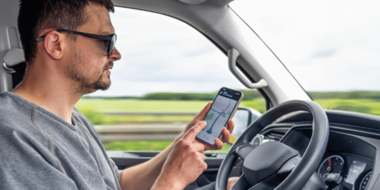 Motorista checando o celular com aplicativo de navegação, representando o trabalho com atividade remunerada.
