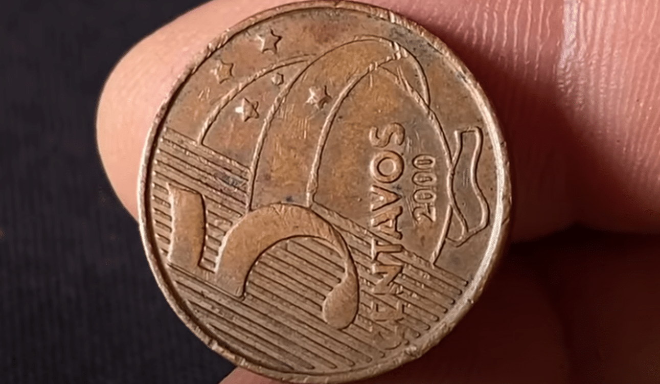 Close-up da moeda de 5 centavos do ano 2000, com o lado do valor (reverso) virado na horizontal, um erro de cunhagem que a torna valiosa.