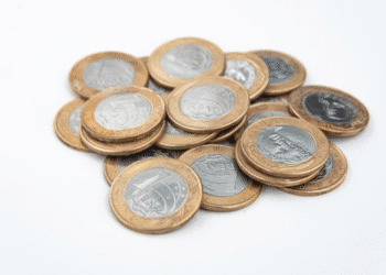 Montinho de moedas de um real (R$ 1,00) em fundo branco, representando dinheiro e o valor potencial de itens raros de colecionismo.