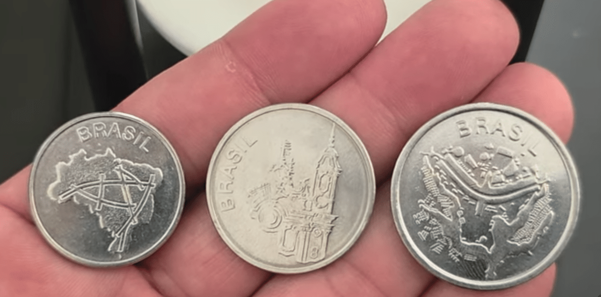 Verso das três moedas de Cruzeiros raras, mostrando as representações históricas: o mapa do Brasil e a integração rodoviária (10 Cruzeiros), a Igrejinha de São Francisco de Assis (20 Cruzeiros) e o Plano Piloto de Brasília (50 Cruzeiros).