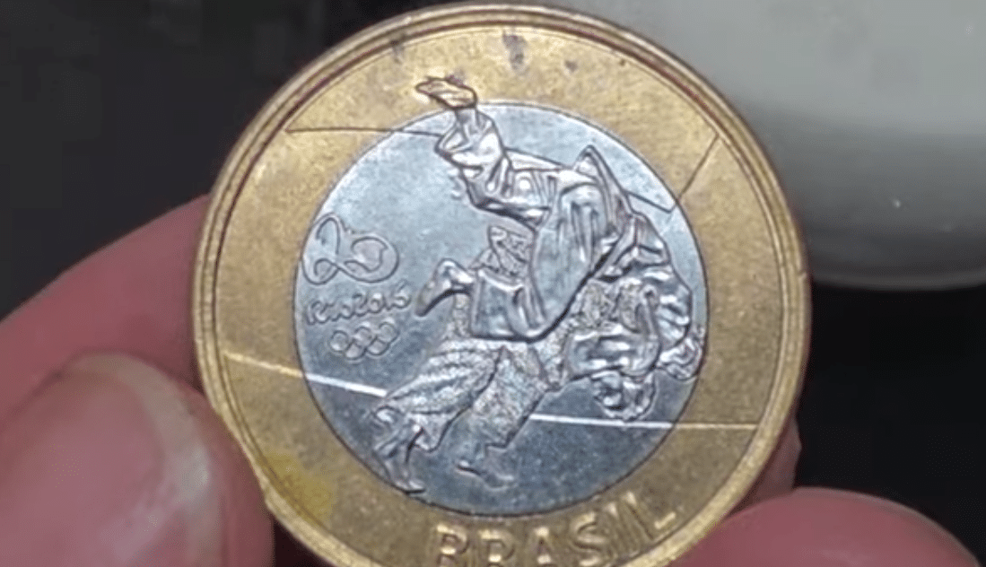 Moeda 1 Real Judô - Rara Data Marcada Imagem de alta resolução da moeda de 1 Real comemorativa das Olimpíadas Rio 2016, mostrando a modalidade Judô. Esta versão é procurada pelo erro de fabricação em que a data aparece marcada em local incomum.