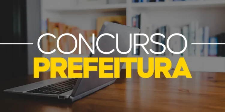 Computador em mesa de madeira com texto Concurso Prefeitura em destaque branco e amarelo, fundo desfocado.
