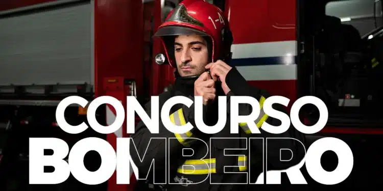 Bombeiro com capacete vermelho e uniforme preto em frente a caminhão de bombeiros