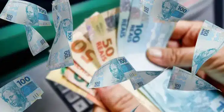 Pessoa segurando notas de reais após saque em caixa eletrônico no Brasil.