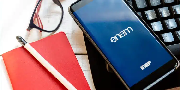 Smartphone exibindo o logo do ENEM sobre um teclado, com materiais de estudo (caderno, lápis e óculos) ao lado, simbolizando a preparação digital e o foco nos temas mais cobrados de Matemática e Física para 2025.