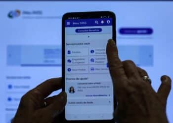 Pessoa usando o aplicativo Meu INSS no celular, acessando informações sobre benefícios.