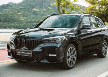 BMW X1 M Sport preto em movimento na beira-mar com grade frontal característica e design esportivo