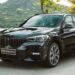 BMW X1 M Sport preto em movimento na beira-mar com grade frontal característica e design esportivo