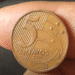 Close-up de uma mão segurando uma moeda de 5 centavos do ano 2000, destacando a raridade do item para colecionadores.