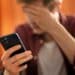 Pessoa com expressão de preocupação segurando um celular, possivelmente alertada por mensagem sobre um vírus de celular.