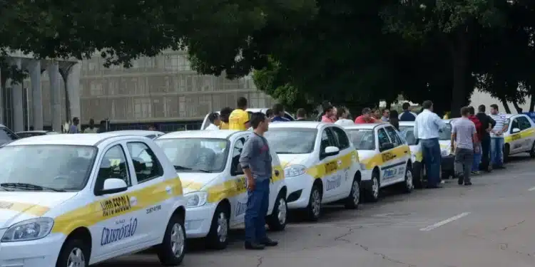 Imagem de carros de autoescola alinhados com pessoas em um ponto de encontro, simbolizando a mudança nas regras da CNH, com a proximidade do fim da obrigatoriedade da autoescola.