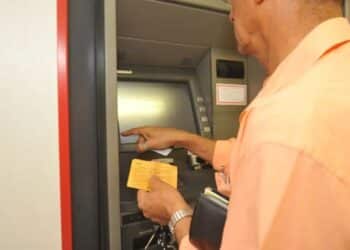 Homem digitando no caixa eletrônico, ilustrando a necessidade de novas regras dos bancos para combater golpes e fraudes em contas bancárias.
