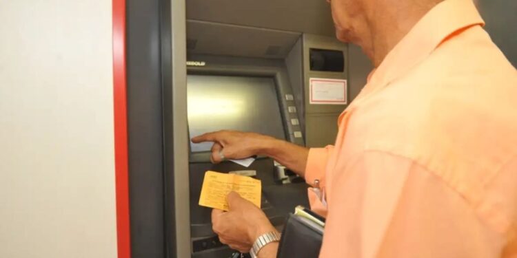 Homem digitando no caixa eletrônico, ilustrando a necessidade de novas regras dos bancos para combater golpes e fraudes em contas bancárias.