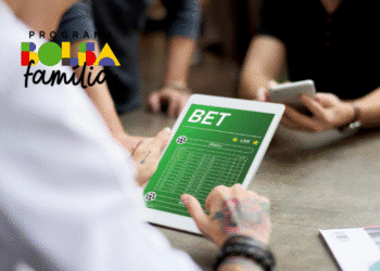 Aposta sendo feita em dispositivo eletrônico, com a imagem de uma tela mostrando informações de apostas esportivas, ao lado de pessoas com celular, com logo do programa Bolsa Família.