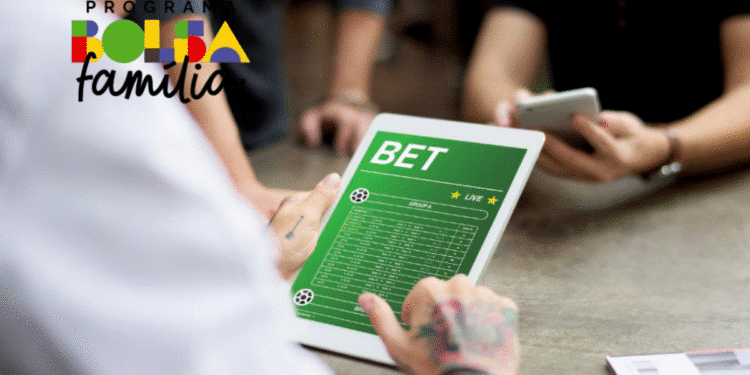 Aposta sendo feita em dispositivo eletrônico, com a imagem de uma tela mostrando informações de apostas esportivas, ao lado de pessoas com celular, com logo do programa Bolsa Família.
