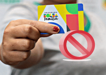 Mão femininas segurando cartão do Programa Bolsa Família com símbolo de proibição sobreposto