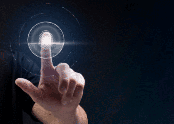 Mão humana tocando uma interface digital de autenticação por impressão digital em fundo escuro