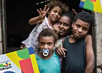 Crianças e familiares com cartões do Bolsa Família, simbolizando a inclusão social e os benefícios do programa em 2025.
