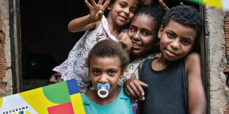 Crianças e familiares com cartões do Bolsa Família, simbolizando a inclusão social e os benefícios do programa em 2025.