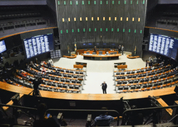 Visão ampla do plenário vazio da Câmara dos Deputados com telas digitais e poucos presentes