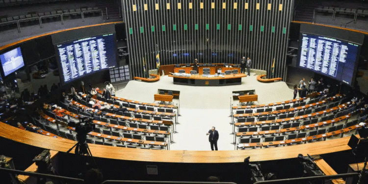 Visão ampla do plenário vazio da Câmara dos Deputados com telas digitais e poucos presentes