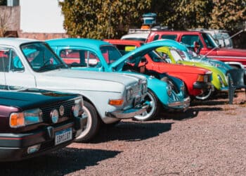 Carros clássicos coloridos estacionados em uma rua.