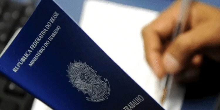 Carteira de Trabalho da República Federativa do Brasil sendo segurada enquanto uma pessoa escreve ou assina