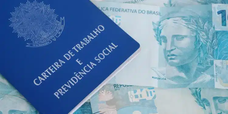 Carteira de Trabalho e Previdência Social sobre várias cédulas de dinheiro em reais brasileiros