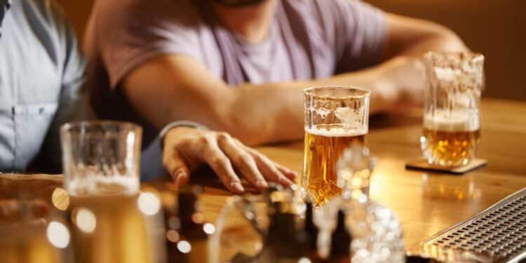 Homens em um bar com copos de cerveja, ilustrando o consumo de bebidas alcoólicas que podem estar contaminadas com metanol.