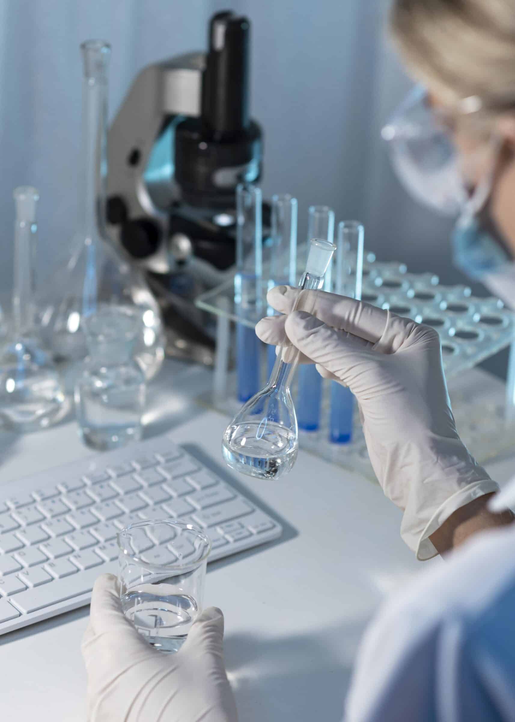 Cientista com luvas e óculos de proteção realizando um teste de metanol em laboratório. A imagem mostra a etapa de reação química para detectar a contaminação em uma amostra líquida.