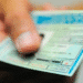 Mão segurando uma Carteira Nacional de Habilitação do Brasil em close desfocado