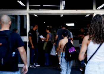 cnu Pessoas jovens entrando em prédio com mochilas nas costas e documentos na mão, ambiente de universidade