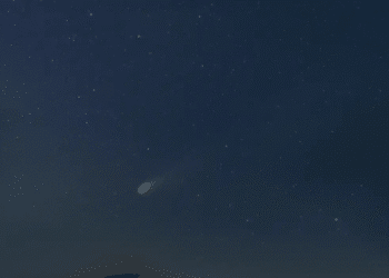 Cometa com cauda brilhante visível no céu noturno repleto de estrelas