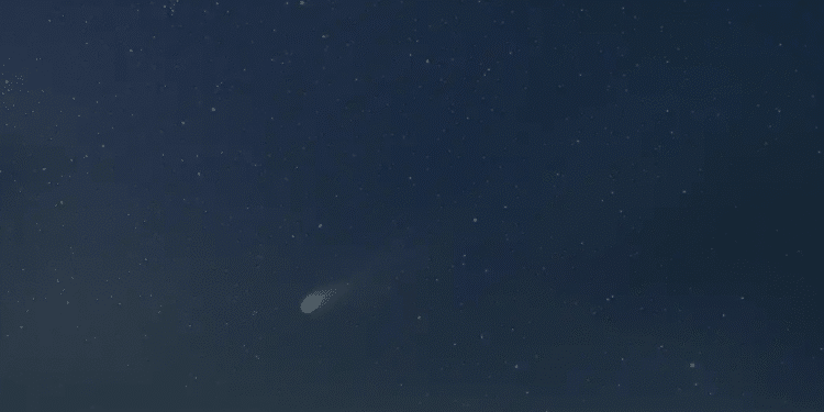 Cometa com cauda brilhante visível no céu noturno repleto de estrelas