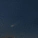 Cometa com cauda brilhante visível no céu noturno repleto de estrelas