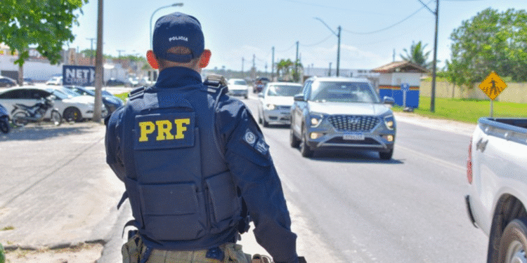 Agente da Polícia Rodoviária Federal vistoriando veículos em movimentada estrada durante o dia