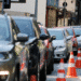 Vários carros estacionados em fila ao longo de uma calçada com cones laranja indicando delimitação
