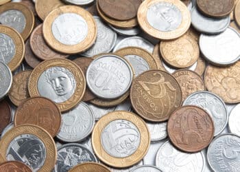 Variedade de moedas brasileiras do Plano Real, com exemplares de 1 Real e centavos, sugerindo a possibilidade de encontrar peças raras com alto valor escondidas no troco.