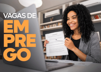 Mulher sorridente em entrevista de emprego online, segurando contrato em frente ao notebook.