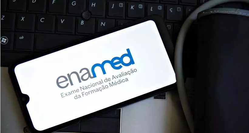 Exame Nacional de Avaliação da Formação Médica (Enamed) 2025 Logo do Enamed exibido na tela de um celular, com fundo de teclado e um aparelho médico ao lado.