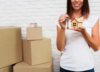 Mulher segurando uma miniatura de casa e chaves, simbolizando novas regras de financiamento imobiliário.