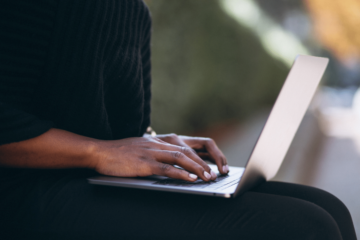 Inscrição Processo Seletivo  Mãos femininas digitando em teclado de laptop prateado sentado ao ar livre