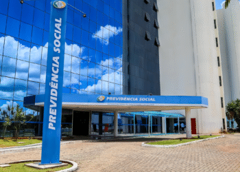 Edifício sede do INSS com fachada em vidro espelhado e placa azul com o nome Previdência Social